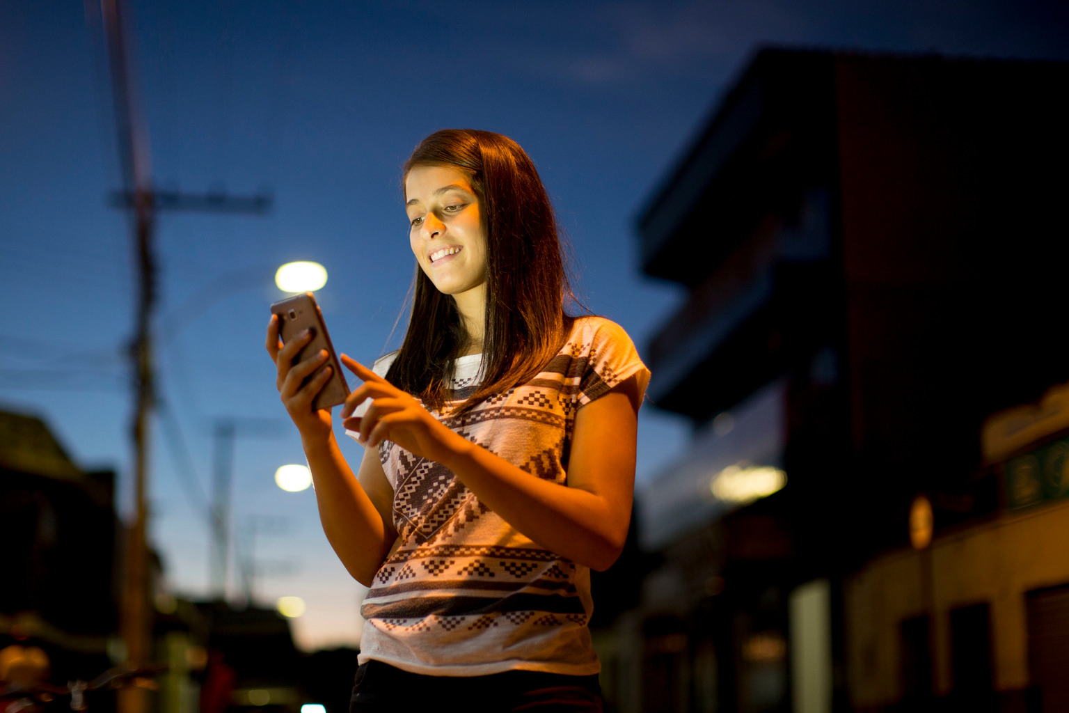 On 30 March 2016, Winny Moreira, 17, checks her mobile phone on a street in Taiobeiras municipality in the Southeastern state of Minas Gerais, Brazil. Winny was born and raised in Taiobeiras, a town of about 30,000, where she lives with her parents, grandparents and 8-year-old brother, Kennedy Caciano. Winny was 10-years-old when she began using the Internet. During high school, she was cyberbullied and reported the incident to the police. Many of her friends were victims of sexting (sending/receiving sexually explicit photographs or messages via mobile phone) and similar online abuse, which included inappropriate photographs being shared throughout the community. Ashamed of the harassment and bullying they endured, several girls stopped attending school altogether and some even moved away from their community. Winny’s friend, Jessica, now 20, was the victim of cyberbullying, social isolation and embarrassment during high school, when inappropriate images from her mobile phone were shared with her peers in school, following the theft of her phone. The device contained nude images she had taken of herself, but had never shared online. Although Jessica reported the theft to the police, they told her nothing could be done without evidence. Winny supported her friend, and became an advocate against online sexual exploitation and cyberbullying. In 2014, she participated in a UNICEF-supported girl’s empowerment programme in Brasilia and in 2015, was a finalist of UNICEF Brazil’s Safe Surf Campaign for her You Tube video “Internet sem Vacilo,” (Internet without Hesitation). The video provided guidance to girls on the topic of cyberbullying, sexting, online digital citizenship and safety. Last year, Winny graduated from Oswaldo Lucas Mendes Public High School and is now preparing for the national college entrance exam. She would like to attend law school so she can continue her advocacy on behalf of her peers.

“I want to study law because I see so much injustic